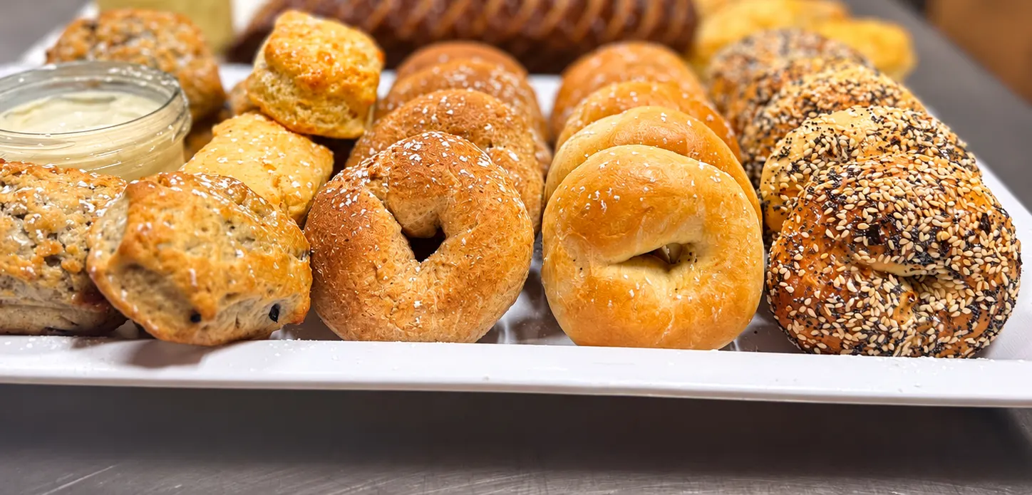 Bagels, scones and loaves laid out with whipped butter and cream cheese